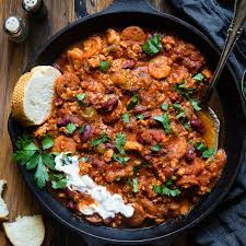 A warm bowl of cajun chili with some bread and sour cream