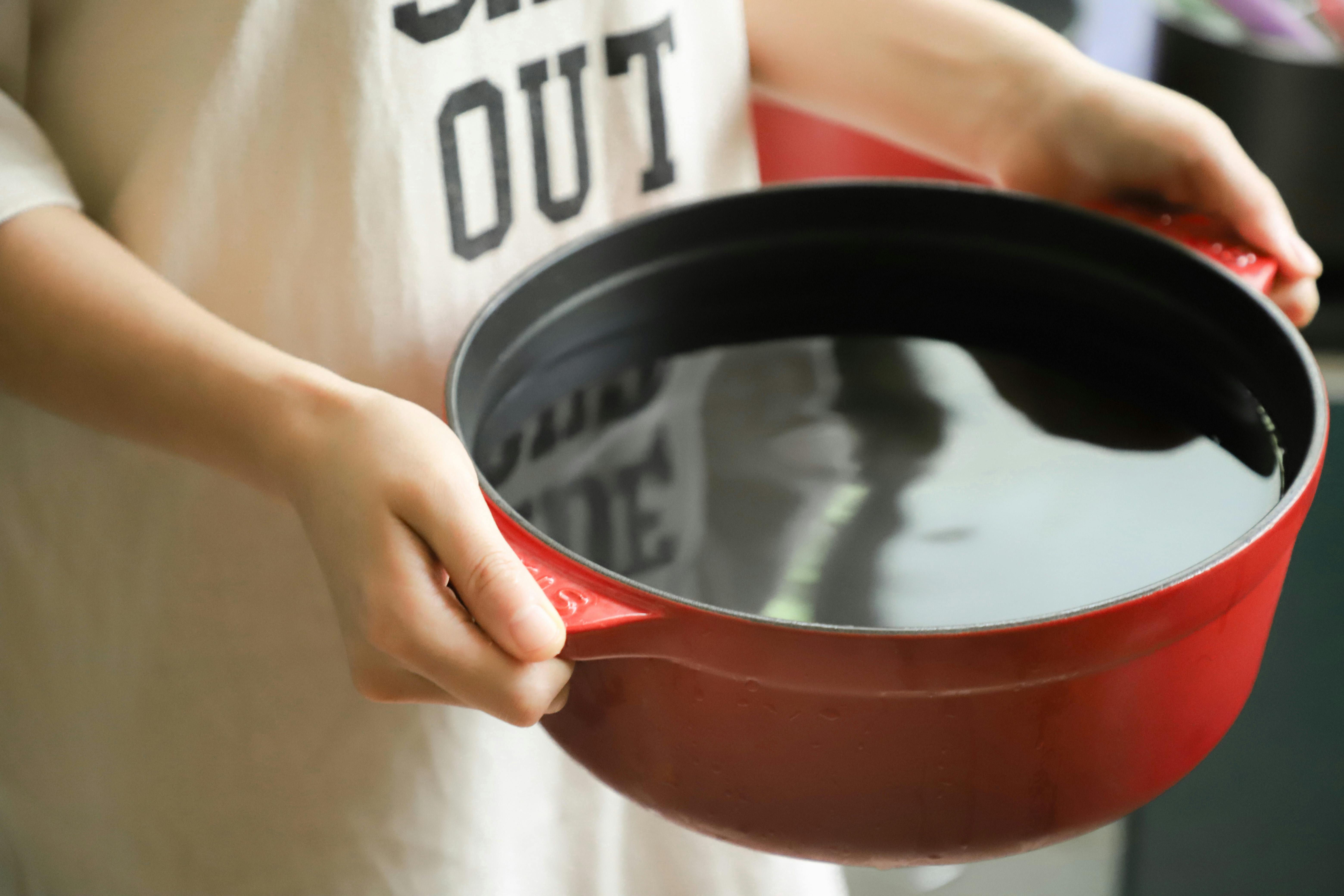 A person holding a bowl of roux that used to make bayou Cajun chili.